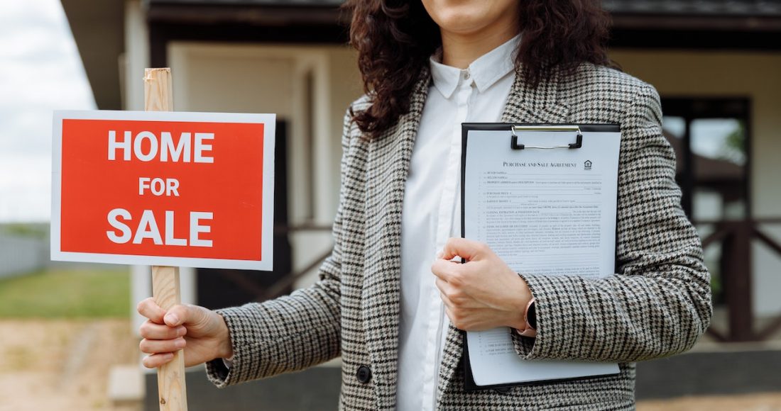 close-up-of-a-woman-holding-a-home-for-sale-sign
