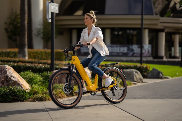 a girl rides in the city on a yellow electric bike