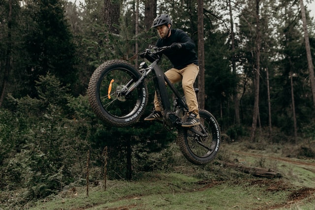 a man jumping on a bicycle in the woods