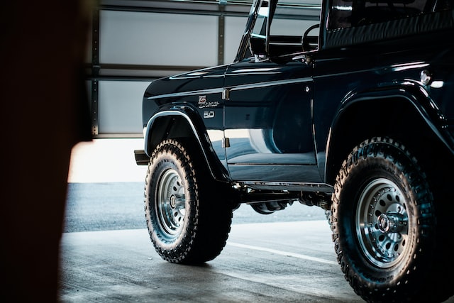 a black jeep is standing in front of a slightly open door in the garage