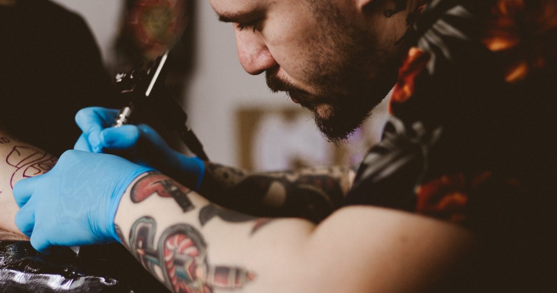 man doing tattoo on person's arm