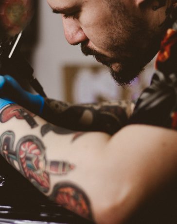 man doing tattoo on person's arm