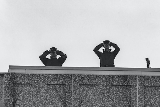 person-in-black-jacket-and-black-pants-sitting-on-concrete-wall