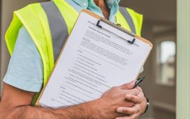 person-in-yellow-reflective-safety-vest-holding-a-pen-and-checklist-of-house-inspection