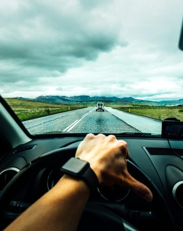 person-driving-car-near-vehicle-under-nimbus-cloudes