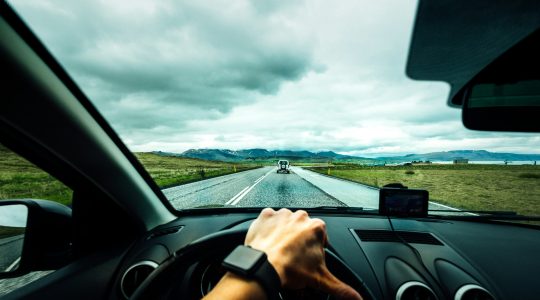 person-driving-car-near-vehicle-under-nimbus-cloudes